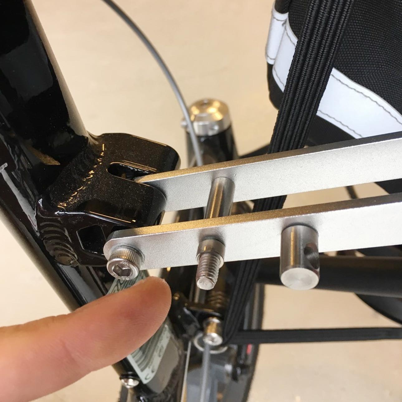 Doigt pointant les boulons de fixation du loquet sur le cadre du Trionic Walker